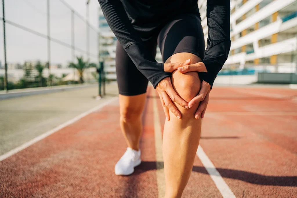 close up of sport woman holding knee orthopaedics and sports medicine